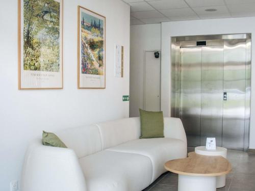 a living room with a white couch and a table at Adagio Access Bordeaux Sud Pessac in Pessac