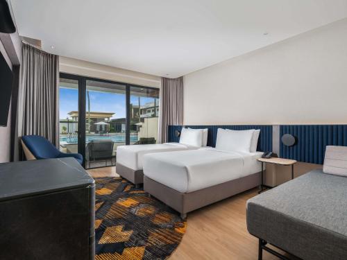 a hotel room with two beds and a television at Novotel Pontianak Convention Centre in Pontianak