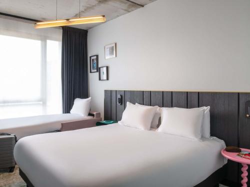 a hotel room with a large white bed and a window at Mercure Quimper Kerlic in Quimper