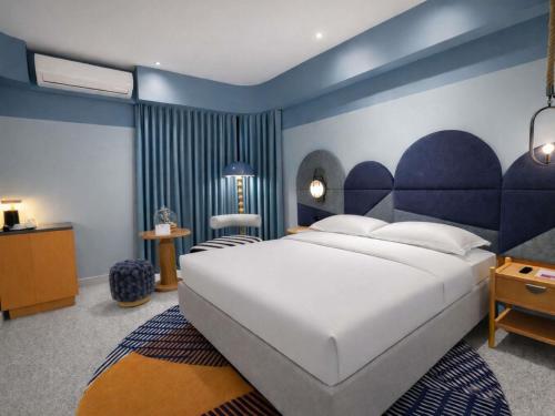 a bedroom with a large white bed and blue walls at Ibis Styles Subic in Olongapo