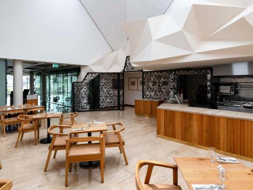 a restaurant with wooden tables and wooden chairs at The Creekside Hotel, Dubai - an Accor Hotel in Dubai