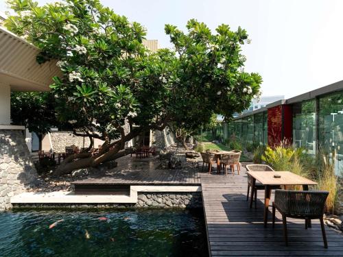 a patio with a tree and a table and chairs at The Creekside Hotel, Dubai - an Accor Hotel in Dubai