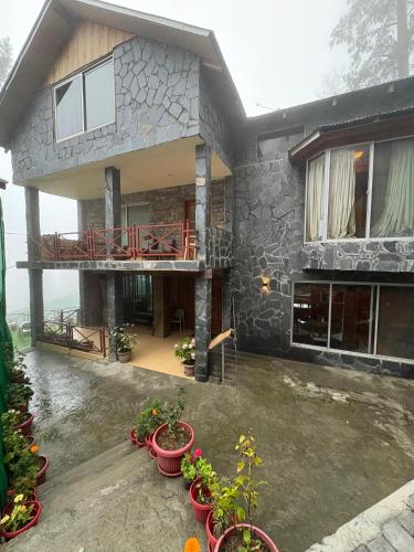 a house with potted plants in front of it at Haven Hilltop Cottage, Dunga Gali in Dunga Gali