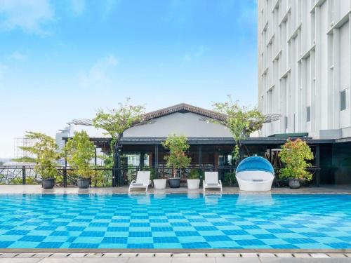 a swimming pool with chairs and a building at Mercure Solo in Solo