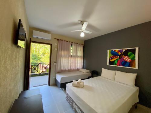 a hotel room with two beds and a window at Hotel Canto do Rio Maresias in Maresias