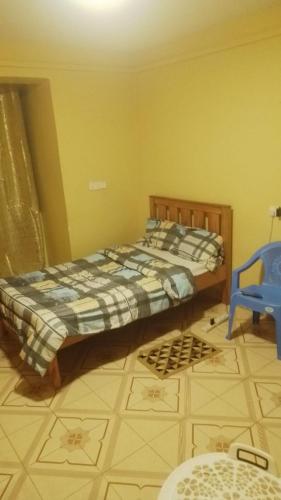 ein Schlafzimmer mit einem Bett und einem blauen Stuhl in der Unterkunft Joymak in Narok