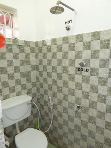 a bathroom with a toilet and a holt gold sign on the wall at Delhi Gardens Hotel in Fort Portal