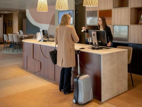 two women standing at a counter in an office at Mercure Auxerre Autoroute du Soleil in Appoigny