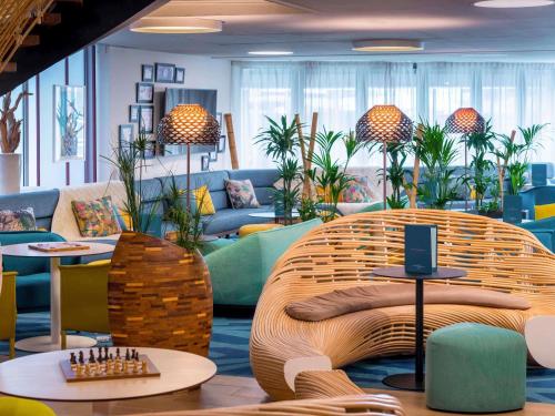 a lobby with a large wicker couch and tables at Mercure Toulouse Centre Saint-Georges in Toulouse