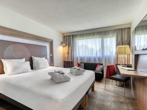 a hotel room with a large bed and a desk at Novotel Paris Nord Expo Aulnay in Aulnay-sous-Bois