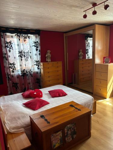 a bedroom with a bed with red pillows on it at Chez Phil et Marie in Pralong