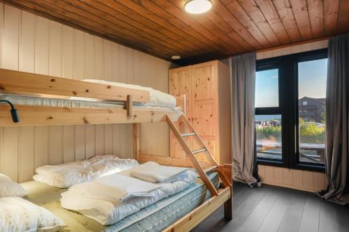 two bunk beds in a room with a window at Cozy Mountain Beito - 18 sengeplasser - bilijard in Beitostøl