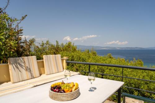 a table with a bowl of fruit and wine glasses at THEA MARE villa in Nea Potidaea