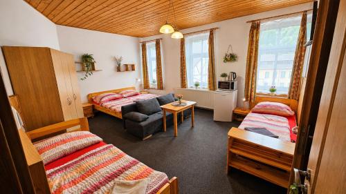 a room with two beds and a living room with a couch at Penzion Na Rozcestí in Janov nad Nisou