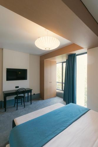 a bedroom with a blue bed and a desk at Proza Hotel & Restaurant in Kutaisi