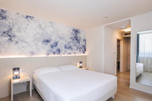 ein Schlafzimmer mit einem weißen Bett und einem Gemälde an der Wand in der Unterkunft Hotel Eden in Sistiana