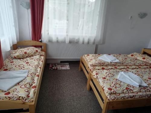 a room with two beds and a window at Sófalvi Vendégház in Sîntimbru