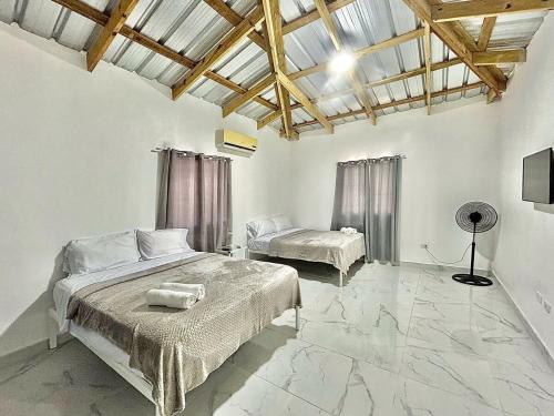 a bedroom with two beds and a ceiling with beams at Mi Refugio 3 in Río San Juan