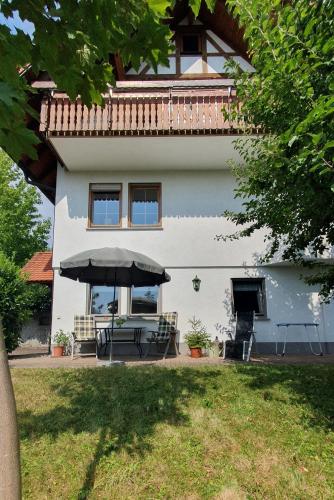 a house with a table and an umbrella in front of it at Ferienwohnung am Rebhang in Sasbachwalden