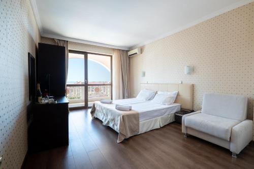 a hotel room with a bed and a chair at Saint George Palace Hotel All-inclusive in Sveti Vlas