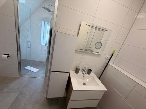 a white bathroom with a sink and a shower at HeideSuite Soltau in Soltau