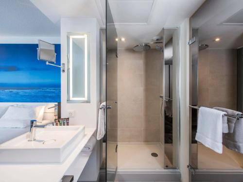 a bathroom with a sink and a shower at Novotel Rennes Alma in Rennes