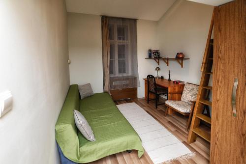 Habitación pequeña con sofá verde y escritorio. en Centrum Apartman, en Pécs