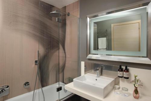 a bathroom with a sink and a shower and a mirror at NH Pisa in Pisa