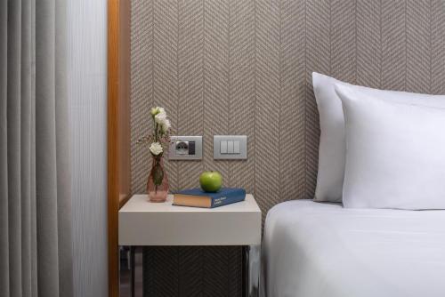 a hotel room with a bed and a table with a book at NH Pisa in Pisa