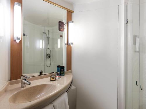 a bathroom with a sink and a mirror at ibis Montbéliard in Montbéliard