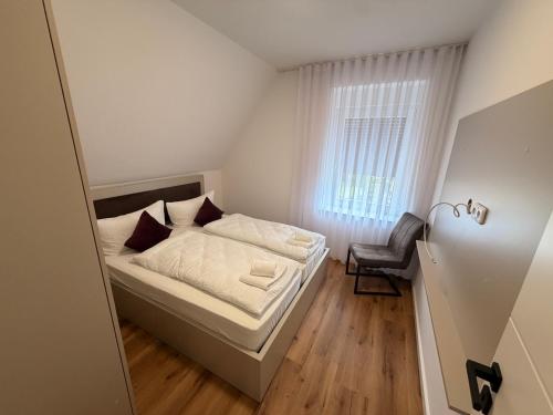 a small bedroom with a bed and a chair at HeideSuite Soltau in Soltau