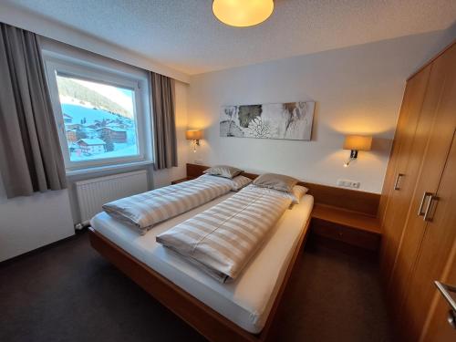 a bed in a room with a large window at Soldanella in Lech am Arlberg