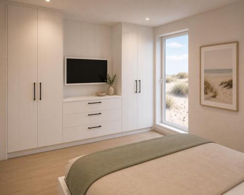 a bedroom with a bed with a television and a window at Kiefernhuus 2 in Norderney