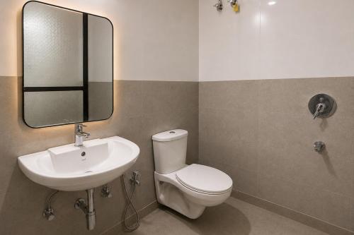 a bathroom with a sink and a toilet and a mirror at Resort SH!VOM Phase-1 in Calangute
