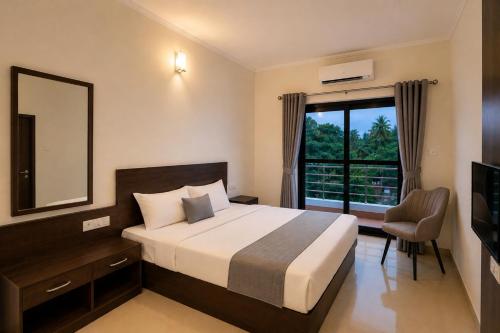 a bedroom with a bed and a window and a mirror at Resort SH!VOM Phase-1 in Calangute