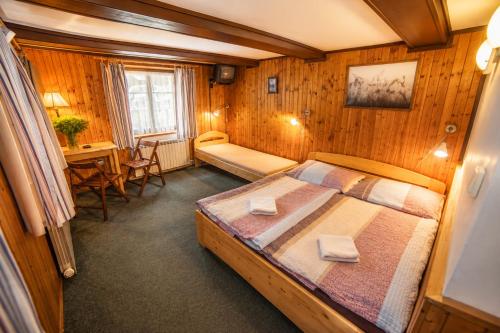 a bedroom with a bed and a desk in a room at Horská chata Hubert in Bedřichov