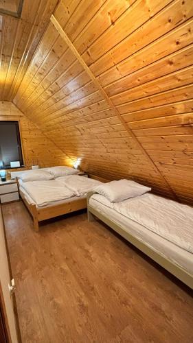 two beds in a room with a wooden ceiling at Ranczo Obozin 62 in Obozin