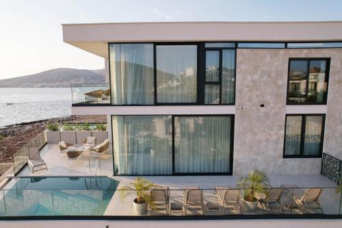 a house with a balcony with a pool and chairs at Nube Luxury Villas in Sarandë