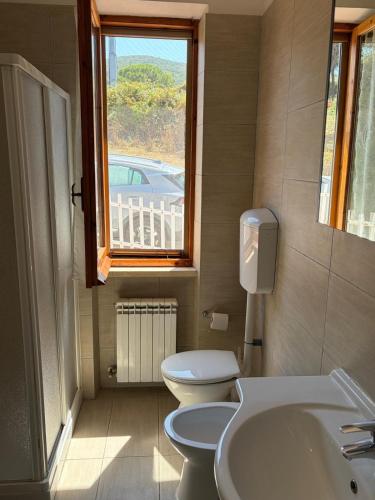a bathroom with a toilet and a sink and a window at Villa Marina primo piano in Rio Marina