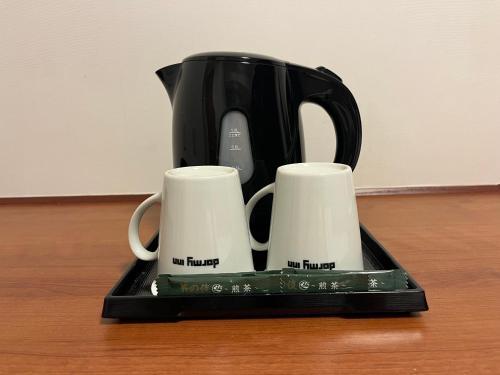 a black coffee pot and two cups on a tray at Dormy Inn Takamatsu in Takamatsu