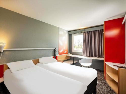 a hotel room with two beds and a desk and a window at ibis Amboise in Amboise