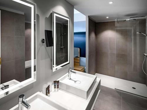 a bathroom with a sink and a mirror and a shower at Novotel Resort & Spa Biarritz Anglet in Anglet