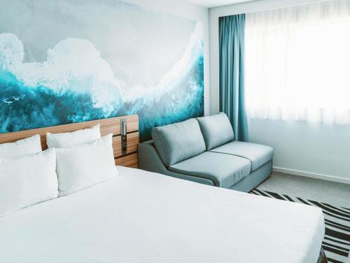 a hotel room with a bed and a chair at Novotel Resort & Spa Biarritz Anglet in Anglet