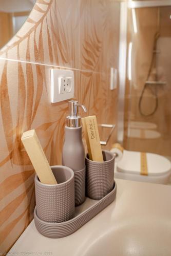 a bathroom sink with a bottle of soap and toothbrushes at Appartamento Bianca in Letojanni