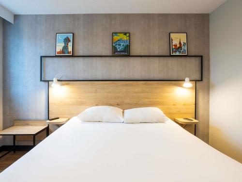 ein Schlafzimmer mit einem großen weißen Bett und zwei Kissen in der Unterkunft Ibis Angoulême Nord in Champniers
