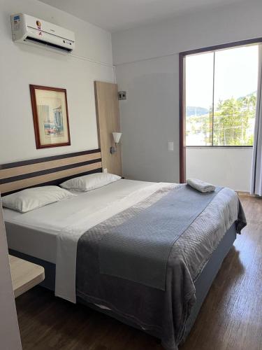 a large bed in a bedroom with a large window at Harbor Inn Jaraguá in Jaraguá do Sul