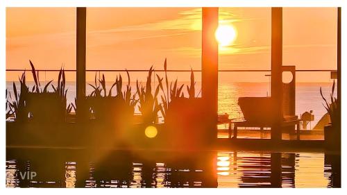 a sunset on a beach with a bench and grass at VIP In Alliance Palace in Batumi