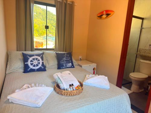 ein Bett mit einem Korb voller Handtücher und einem Fenster in der Unterkunft Casa Sol da Ilha in Angra dos Reis