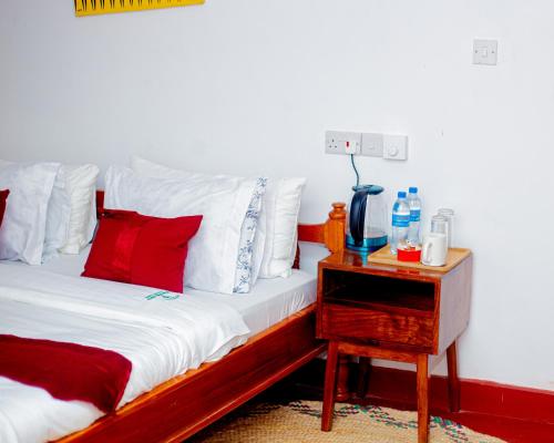 a bedroom with a bed with red and white pillows and a night stand at Furavia Hotel stay in Moshi