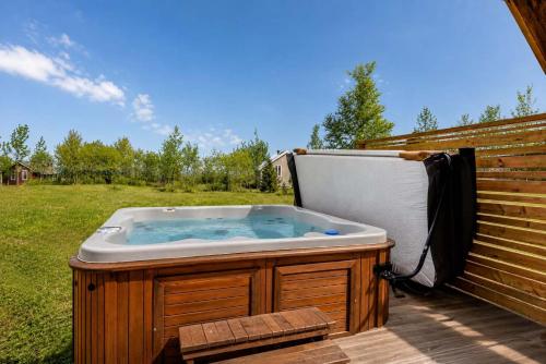 a hot tub sitting next to a wooden fence at Le Haut-Perche - Spa and River View in Petite-Rivière-Saint-François